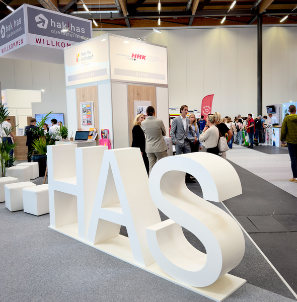 HAS-Buchstaben vor HAK-Ständen mit Besuchern bei einer Messe in Steyr